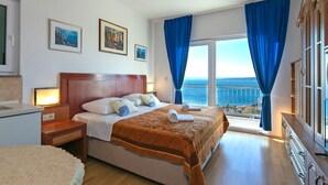 A hotel room with a bed, a nightstand, a dresser, and a view of the sea. - Apartments Marko (Brela)