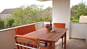 Una mesa y sillas de madera en un balcón con vistas a árboles y edificios.