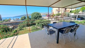 A terrace with a table and chairs, offering a view of the sea and surrounding buildings. - Apartments Ante (Seget)