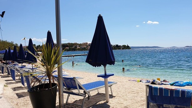 A beach with sun loungers, umbrellas, and a clear view of the sea. - Apartments Ante (Seget)