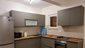 A modern kitchen with grey cabinets, a built-in microwave, a gas stove, and a small oven. - Apartments Ante (Seget)