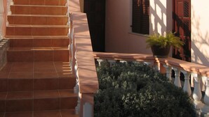 A two-story building with a staircase leading to a balcony. - Apartment Jakov (Nin)