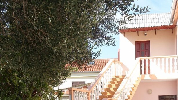 A courtyard with a stone staircase leading to a building with a tiled roof and a balcony. - Apartment Jakov (Nin)