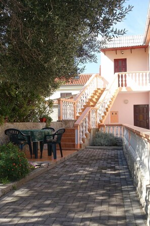 A courtyard with a stone staircase leading to a building with a tiled roof and a balcony. - Apartment Jakov (Nin)