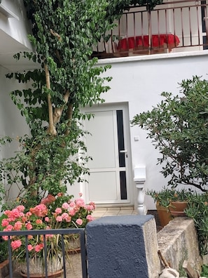 Un balcon avec un pot de fleurs, une porte et une rambarde.