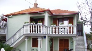 Un edificio de dos plantas con un balcón y una escalera, y una bicicleta estacionada afuera.