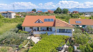 Un immeuble résidentiel avec un toit recouvert de tuiles rouges, un balcon et un espace jardin.