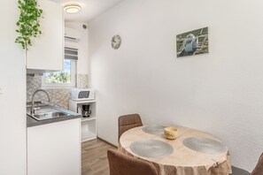 A compact kitchen with a sink, microwave, and a dining area with a table and chairs. - Apartment Danijela (Nin)