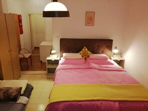 Quarto com cama, luminárias de cabeceira, guarda-roupa, escrivaninha e cadeira.