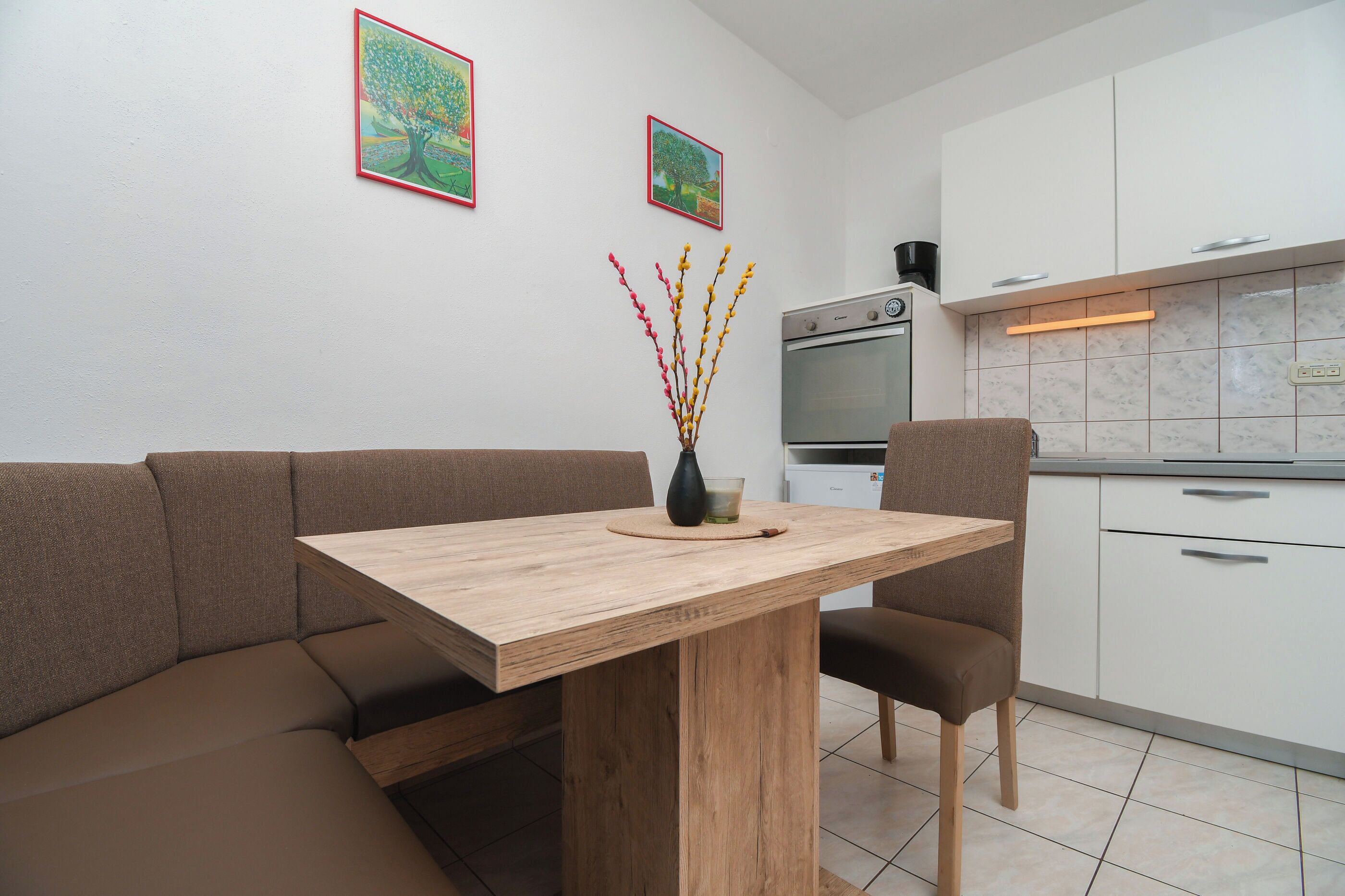 Eine moderne Küche mit weißen Schränken, einem eingebauten Backofen und einem Holzespeisetisch mit zwei Stühlen.