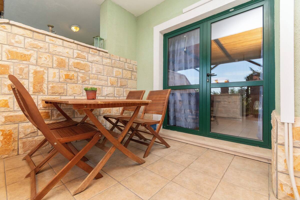 A dining area with a stone wall, wooden table and chairs, and a large window with a view of the outside.