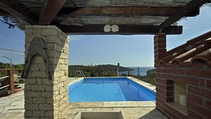 Ein Pool mit Steinmauern und einer Pergola darüber.