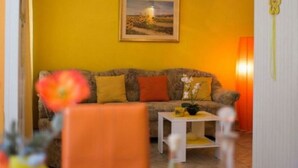 Un salon chaleureux avec un mur jaune, un canapé, une table basse et un tableau.