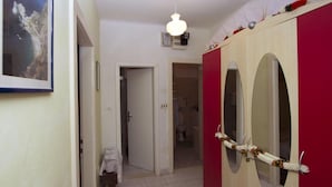 A hallway with a wooden wardrobe, a small table with a cloth, and a framed picture on the wall. - Apartment Brane (Split)