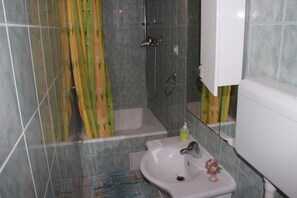 A bathroom with a bathtub, a sink, and a shower curtain. - Apartment Brane (Split)