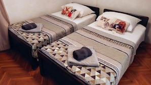 Two single beds with patterned bedding and towels, a wall-mounted light, and a wooden floor. - Apartment Silvana (Sali)
