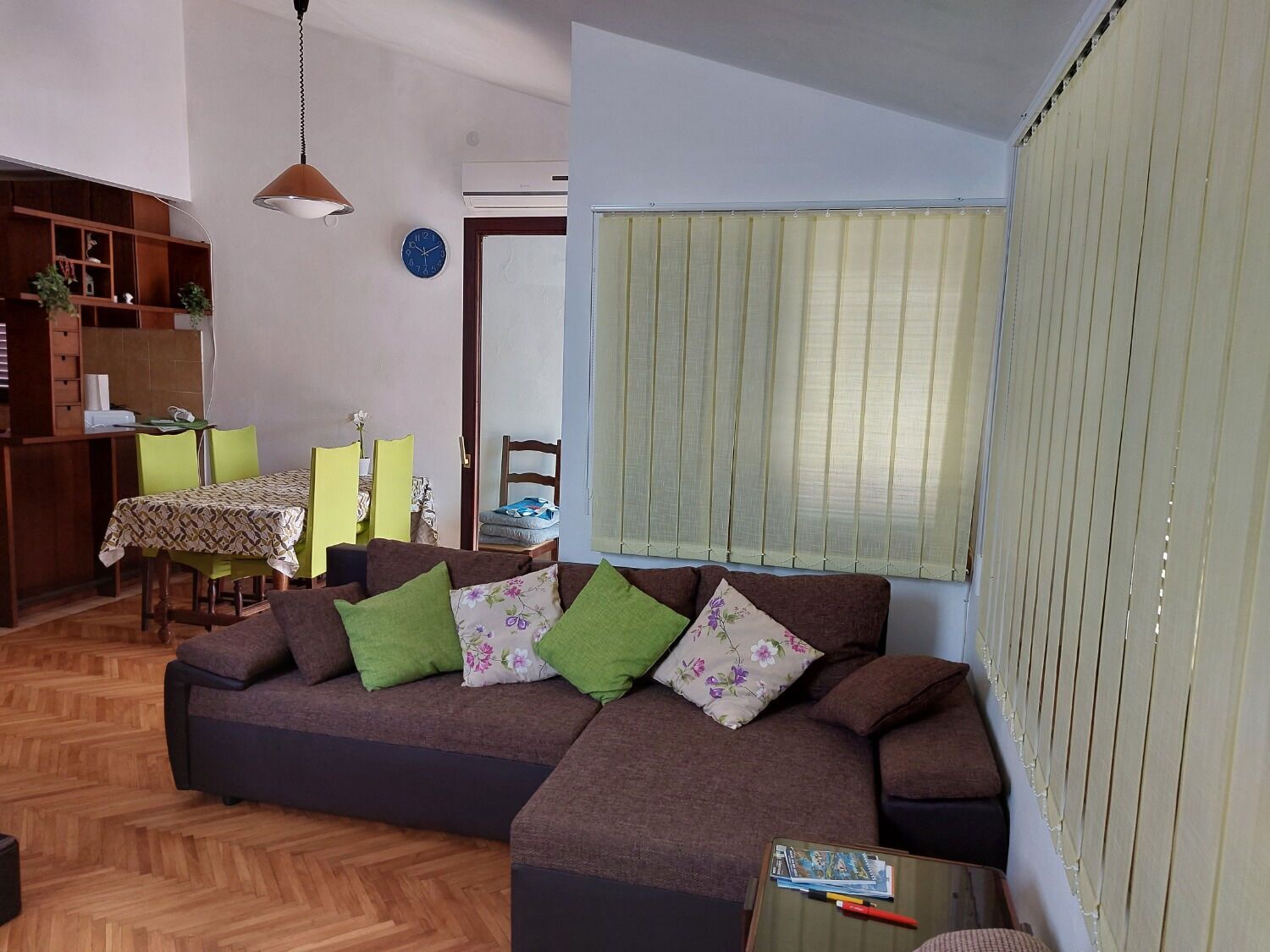 A living room with a sofa, chairs, a dining table, and a bookshelf.