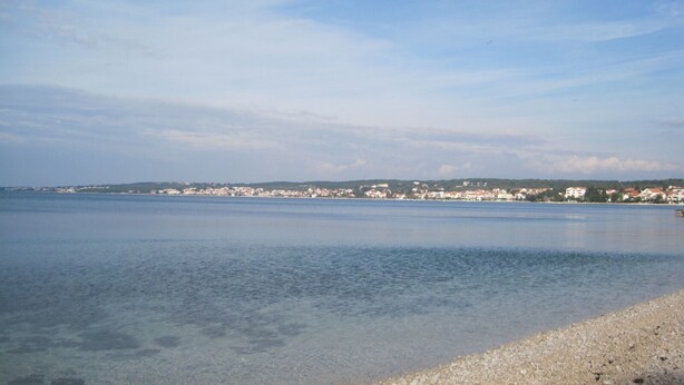 A coastal view with a clear beach and a distant town. - Apartment Ivan (Zadar)