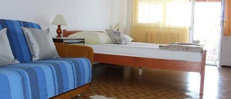 A room with a bed, a sofa, a lamp, and a rug.