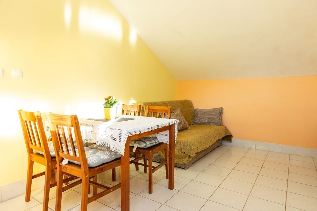 Una habitación acogedora con una mesa de comedor, sillas, un sofá y una pequeña planta en maceta.
