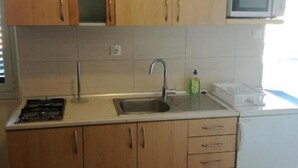 A kitchen with wooden cabinets, a stainless steel sink, a microwave, and a dishwasher. - Apartment Antonio (Murter-Kornati)