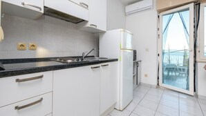 A modern kitchen with white cabinets, a black countertop, and a built-in oven. - Apartments Mari (Dugi Rat)