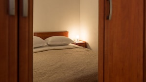 Ein Schlafzimmer mit einem Bett, Kissen, einem Nachttisch mit Lampe und einer Holztür.
