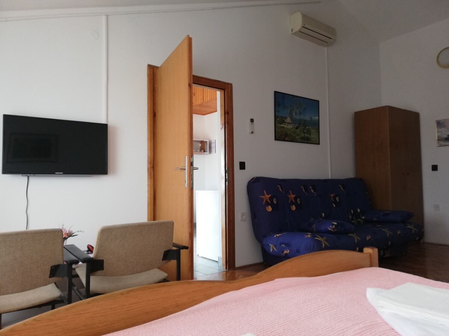 Una camera d'albergo con un letto, un divano, una TV e un accesso al bagno.