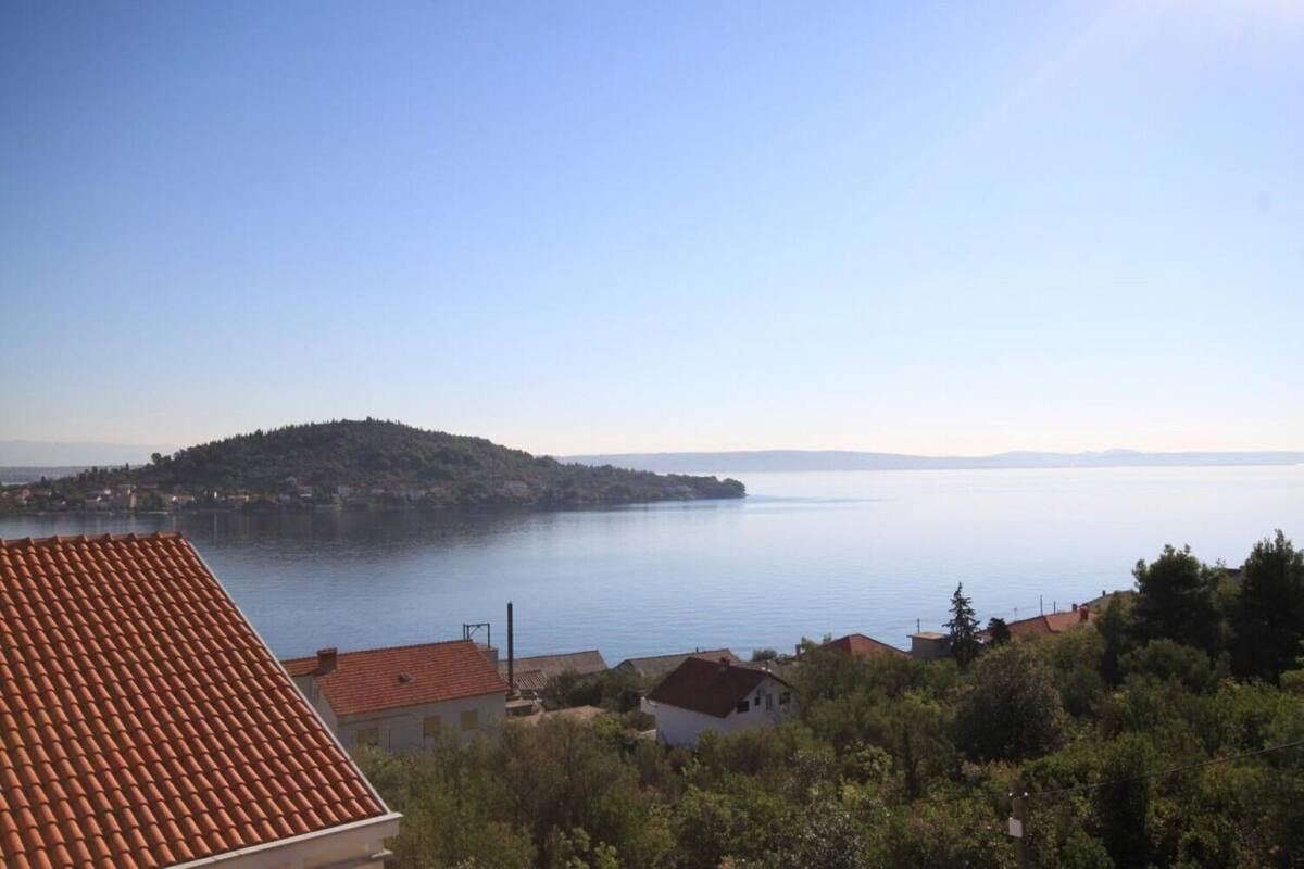 Küstensicht mit blauem Himmel, einer fernen Insel und ruhiger See.