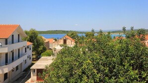 A coastal building with a red-tiled roof, a balcony, and a view of the sea. - Apartment Ljube (Orebic)