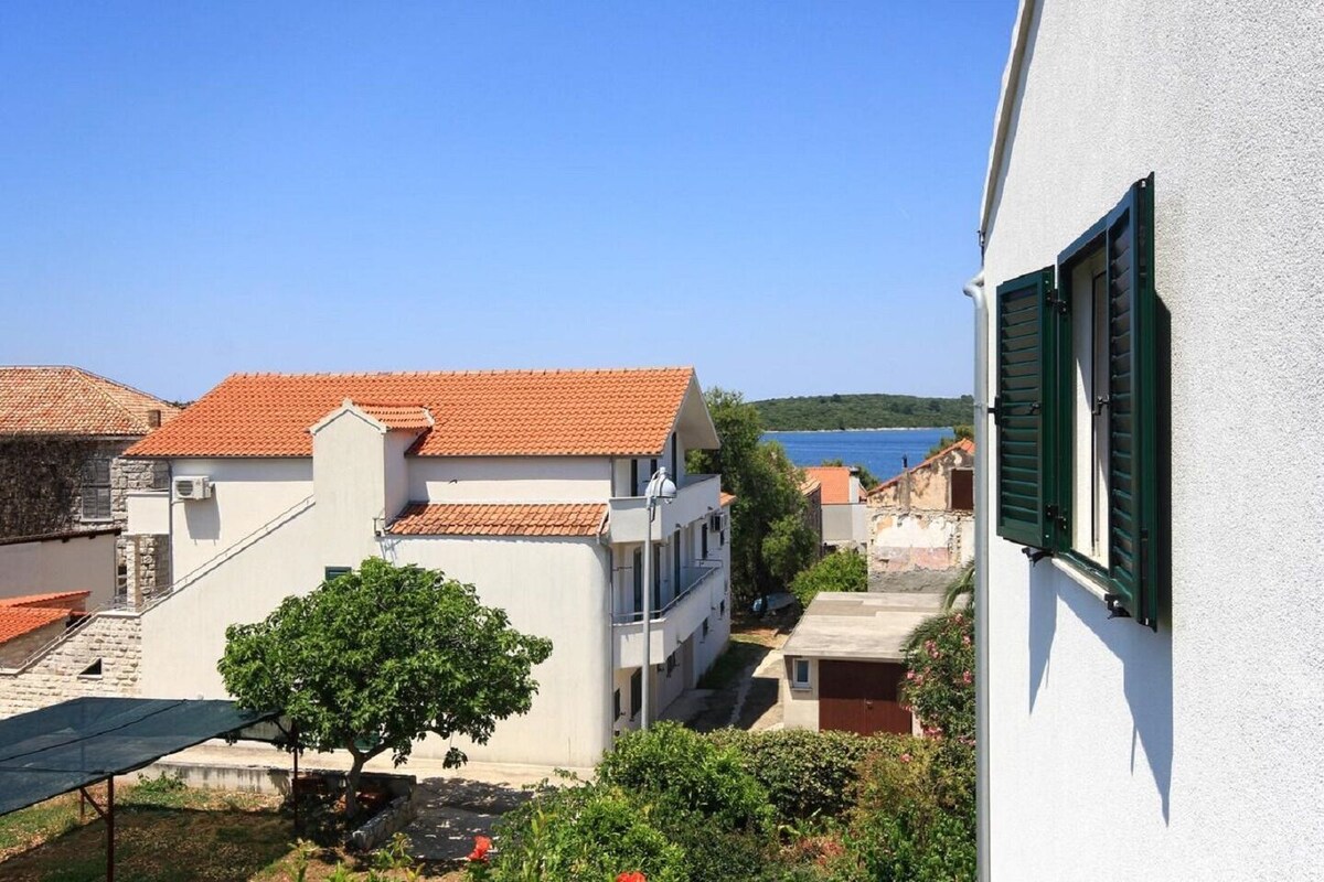 Ein Küstengebäude mit rotem Ziegeldach, weißen Wänden und grünen Fensterläden.