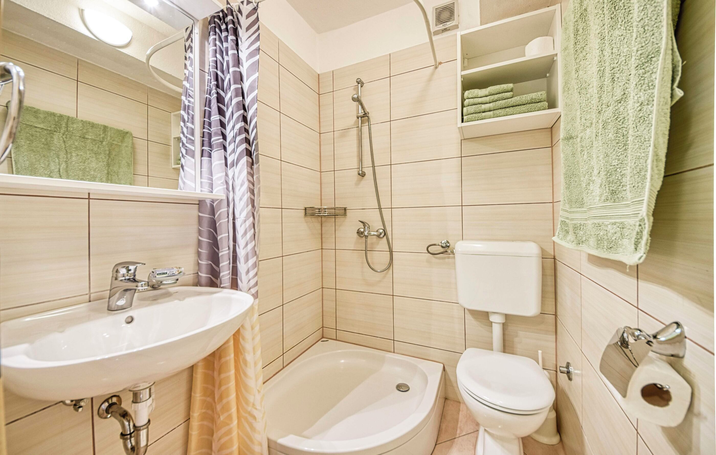 Een badkamer met een wastafel, toilet, douche en een handdoekrek.