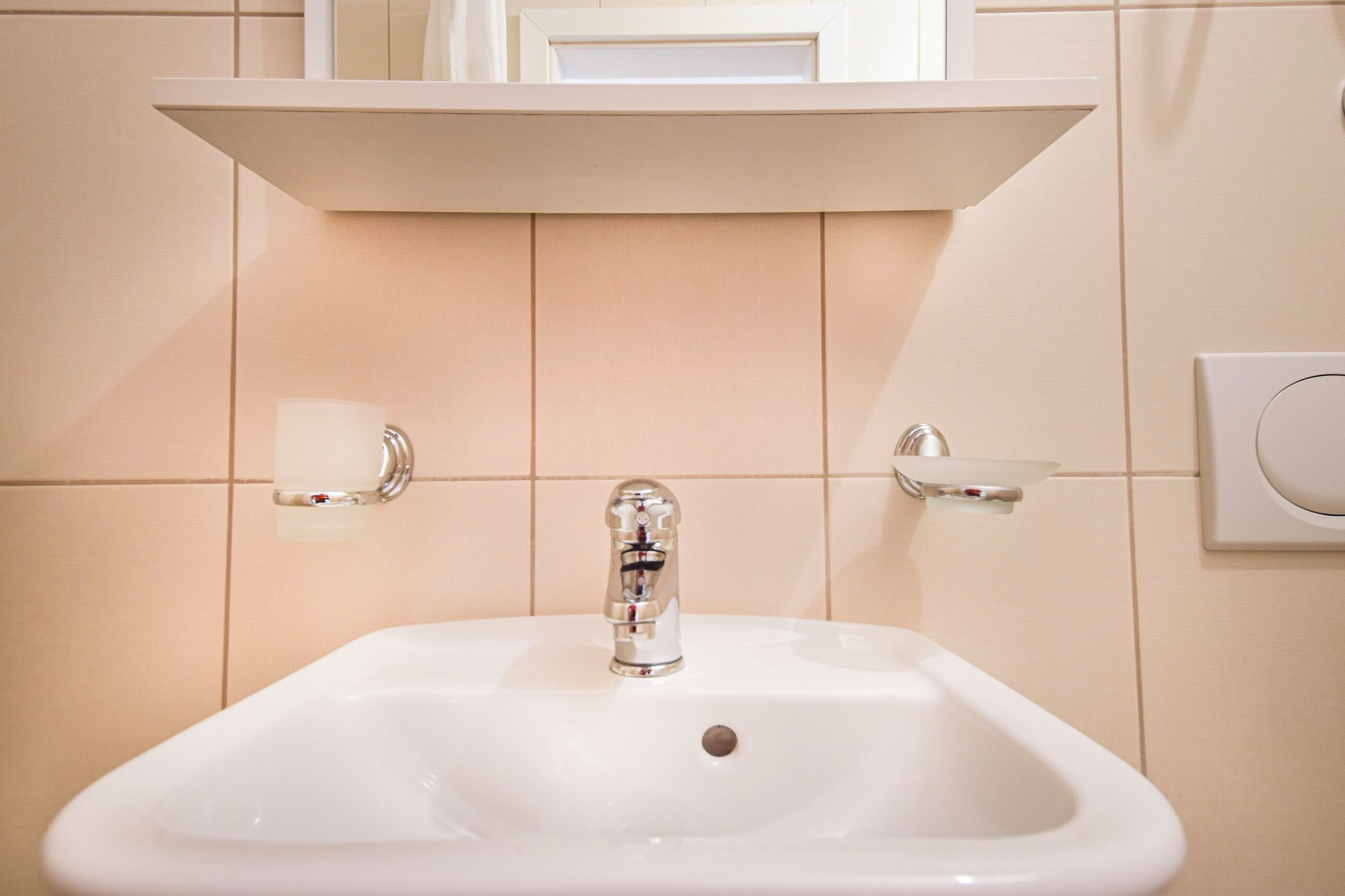 A bathroom sink with a chrome faucet, a soap dish, and a towel holder on the wall.