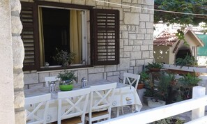 A balcony with a table and chairs, potted plants, and a view of the sea. - Apartments Marija (Supetar)