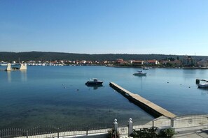 A marina with boats docked, a clear sky, and a distant town with houses. - Apartments Let (Sukosan)