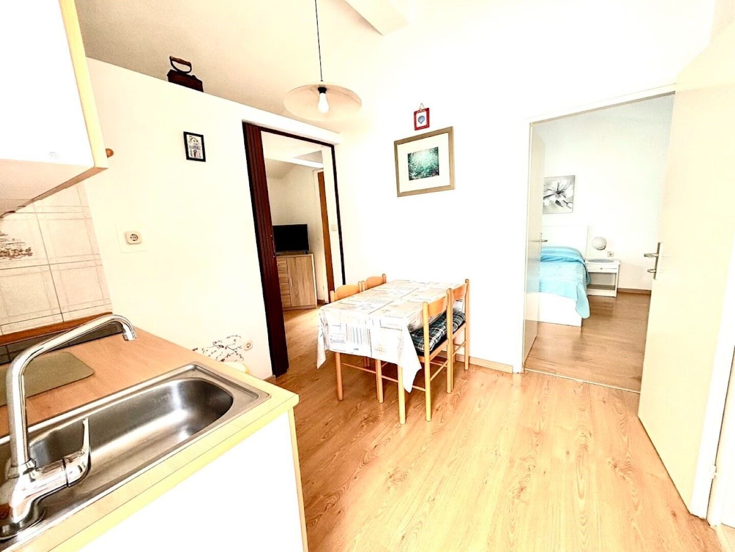 Una cocina compacta con lavamanos y un comedor con mesa y sillas.