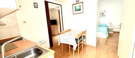 Una cocina compacta con lavamanos y un comedor con mesa y sillas.