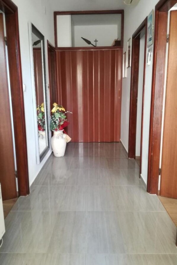 A hallway with wooden paneling, a potted plant, and a cross on the wall. - Apartments Let (Sukosan)