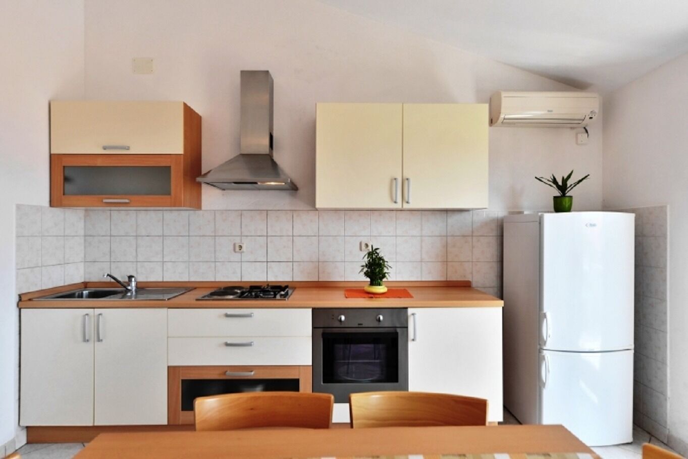 A modern kitchen with white cabinets, a gas stove, an oven, and a refrigerator.