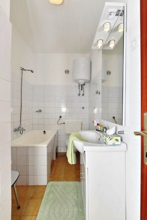 Un baño pequeño con bañera, lavamanos e inodoro.