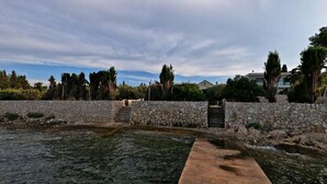 A stone wall with a gate leading to a pool area. - Apartment Mili (Preko)