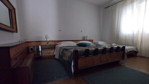 A bedroom with a wooden bed, a nightstand, a dresser, and a mirror. - Apartment Mili (Preko)