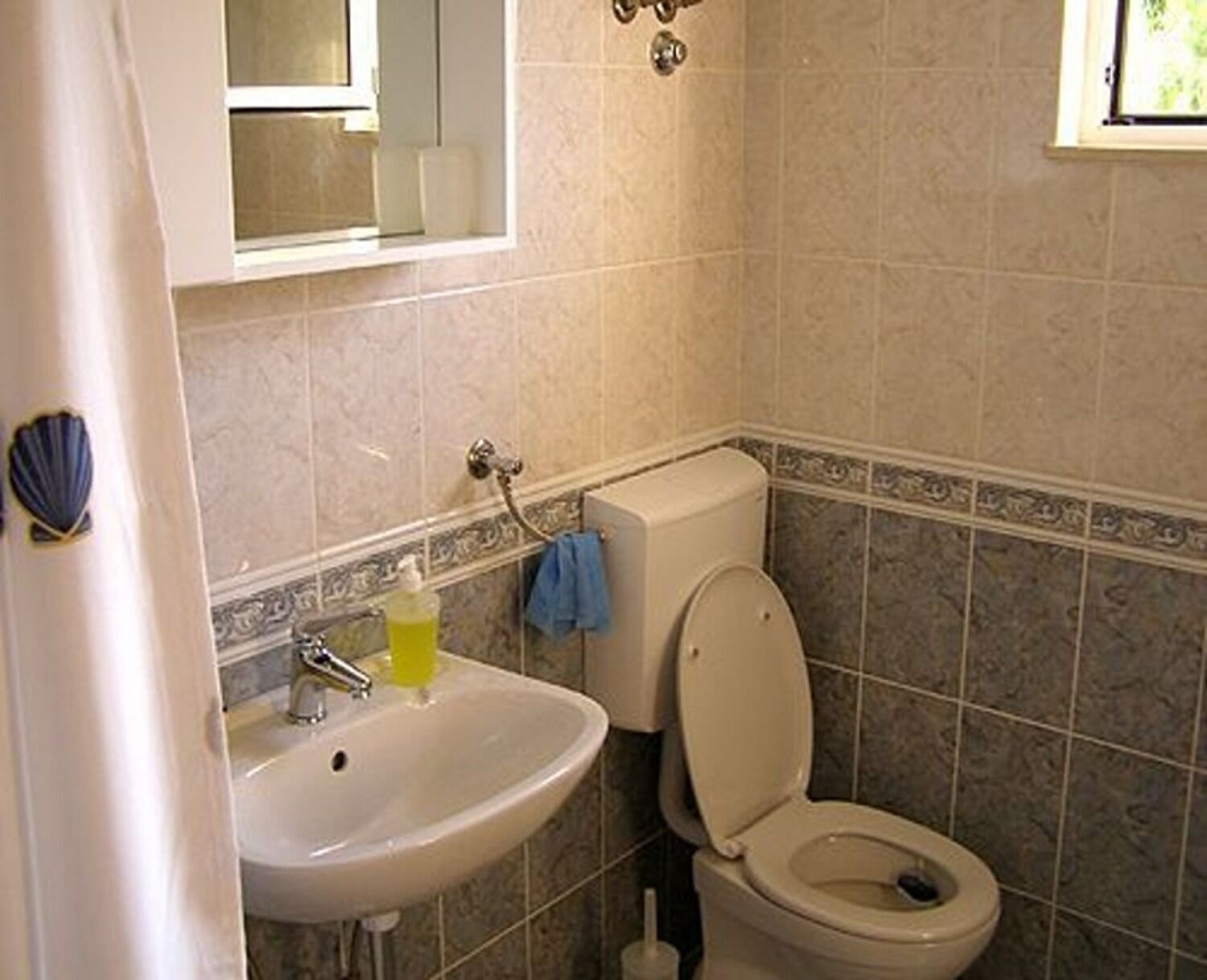 Un baño con lavamanos, inodoro y espejo.
