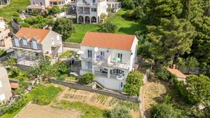 A two-story house with a red-tiled roof, surrounded by greenery and other residential buildings. - Apartments Mat (Zupa dubrovacka)