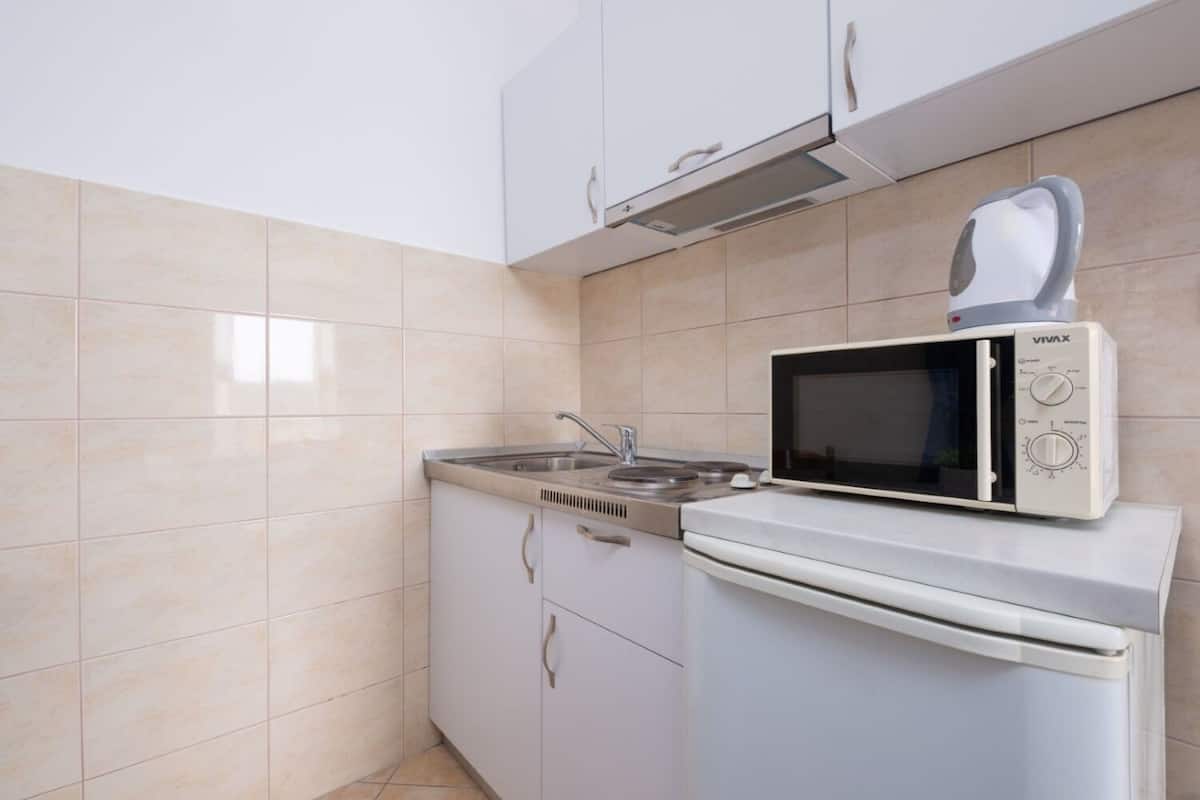 A compact kitchen with a microwave, stove, and sink.