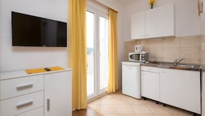 A compact kitchen with white cabinets, a microwave, and a small refrigerator. - Apartments Mat (Zupa dubrovacka)