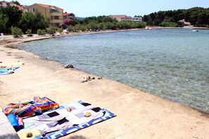 Una spiaggia con acque cristalline, una costa sabbiosa e edifici sullo sfondo.