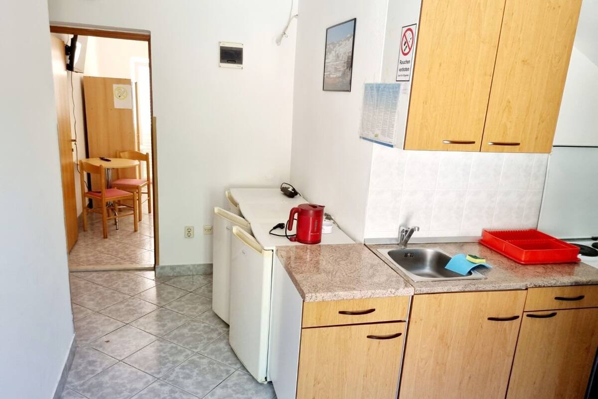 A compact kitchen with wooden cabinets, a sink, and a small dining area with a table and chairs.