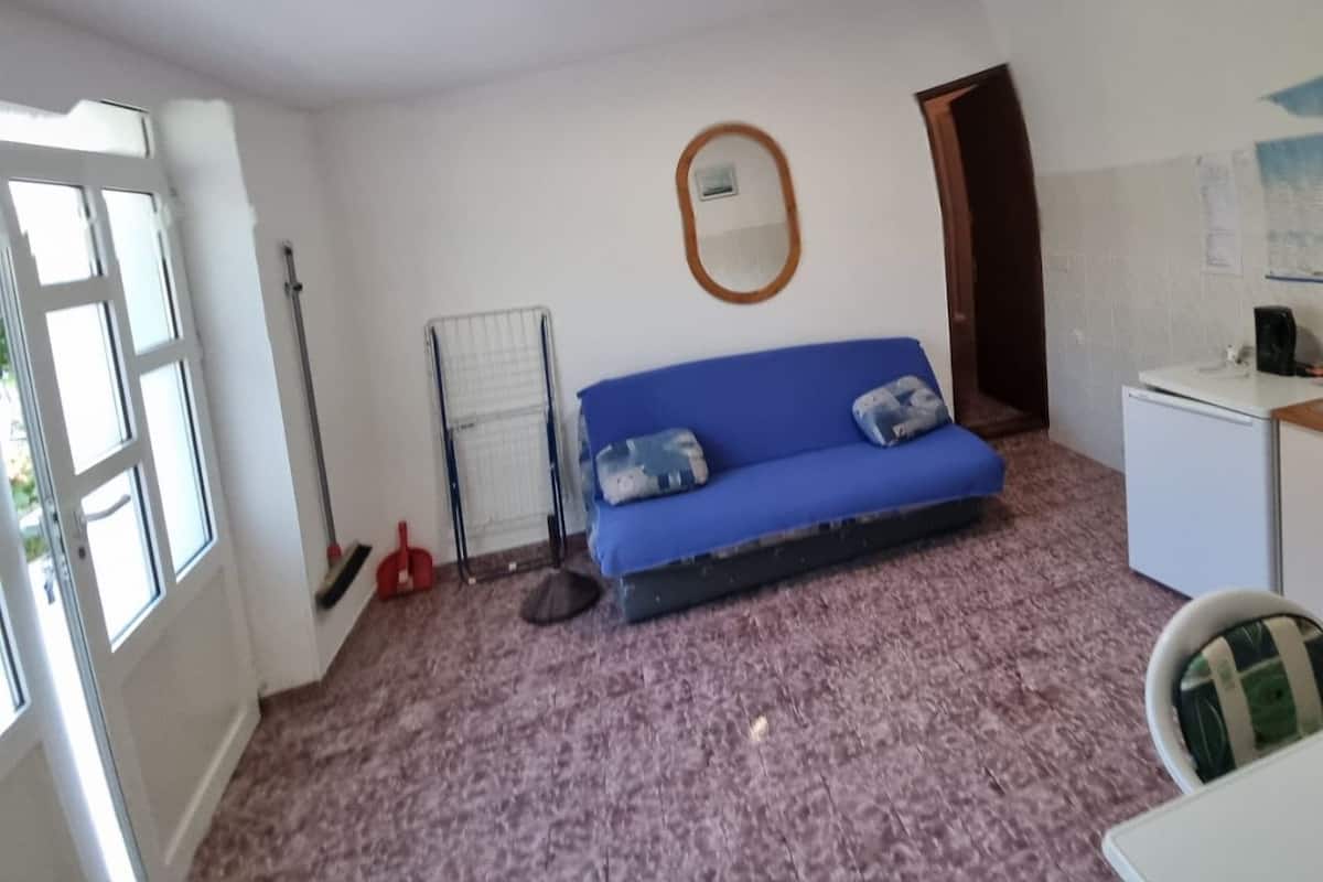 A room with a blue sofa, a small table, a radiator, a mirror, and a door.