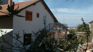 A two-story house with a red-tiled roof, a balcony, and a chimney. - Apartment Vido (Trpanj)